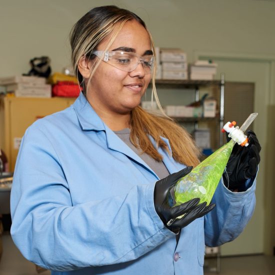Woman in personal protective equipment holding a separatory funnel